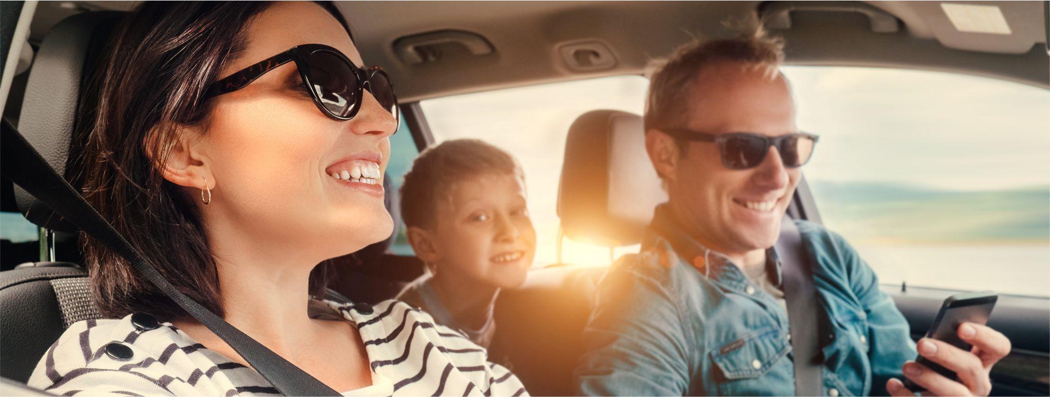Une famille conduisant dans une voiture portant des lunettes de soleil en souriant